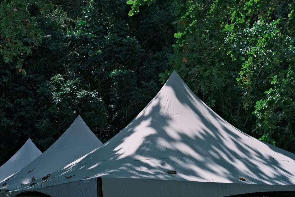 Minimalistische poeftent onder blauwe zomerlucht.